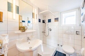 Un baño moderno con lavamanos, inodoro y ducha.