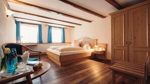 A bedroom with a wooden bed, a desk with a chair, a radiator, and a wardrobe. - Hofgut Himmelreich (Kirchzarten)