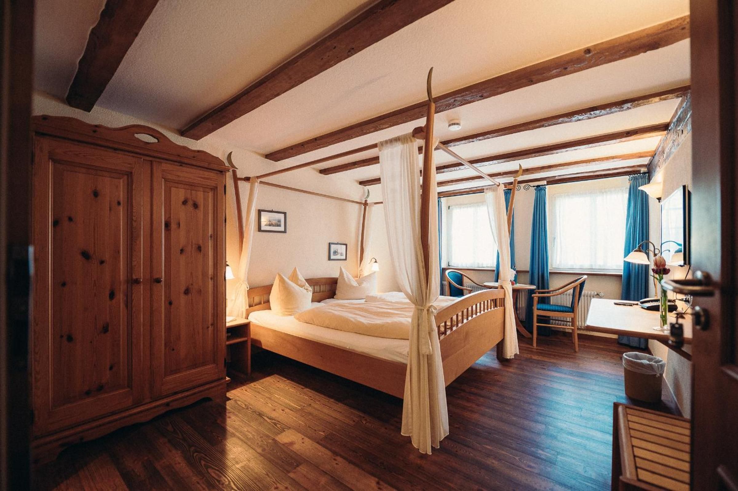 A bedroom with a four-poster bed, wooden furniture, and a large wardrobe.