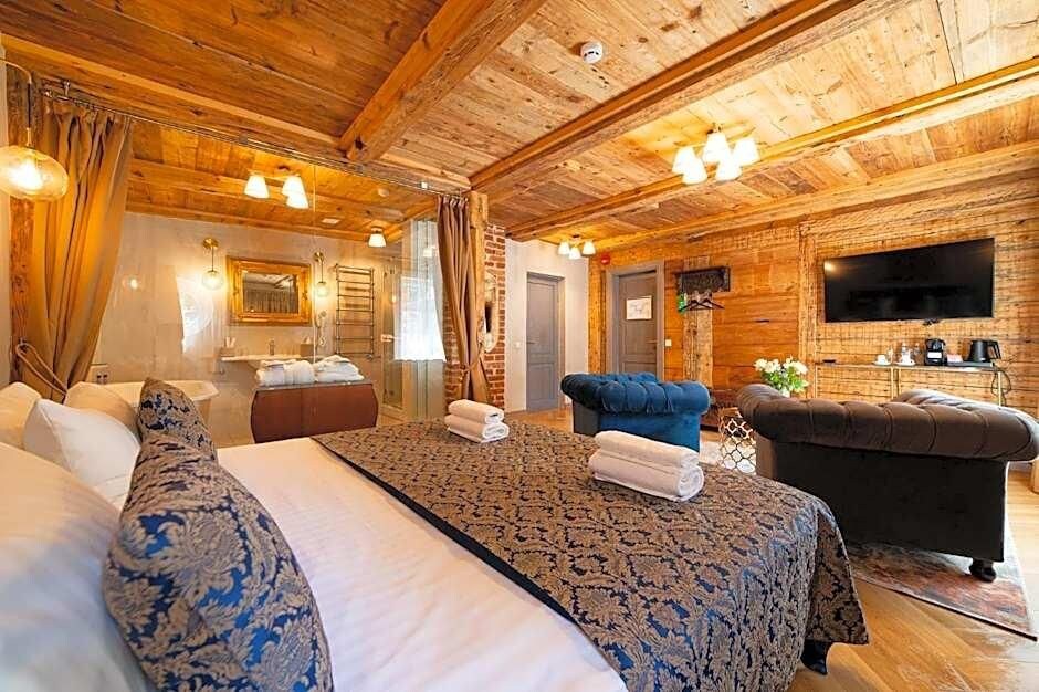 Ein Hotelzimmer mit einem großen Bett, einer Couch, einem Fernseher und einer Holzbalkendecke.