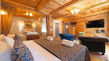 Habitación de hotel con una cama grande, un sofá, un televisor y techo de madera.