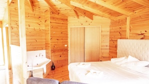Een slaapkamer in een houten blokhut met een bed, nachtkastje en een stoel.