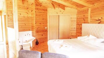 A wooden cabin bedroom with a bed, a bedside table, and a chair.