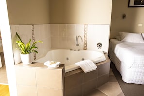 A bathroom with a bathtub, a potted plant, and a towel on the edge. - Little Norfolk Bay Events And Chalets (Taranna)