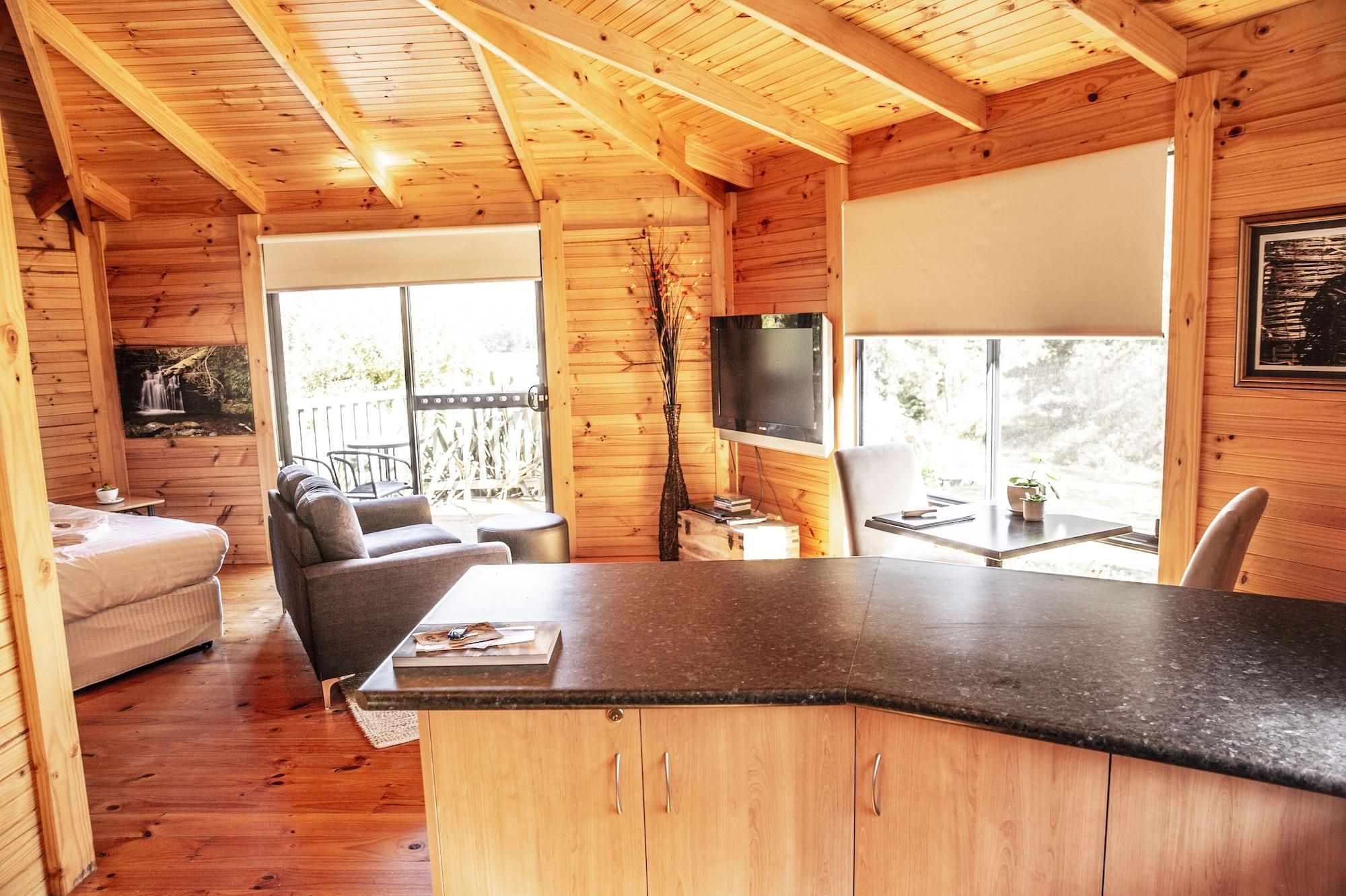 L'intérieur d'un chalet en bois comprend un coin repas, un canapé, un téléviseur et offre une vue sur l'extérieur.