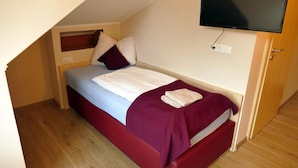 A single bed with a headboard, a flat-screen TV mounted on the wall, and a power outlet on the wall. - Seehotel Bad Kleinen (Bad Kleinen)