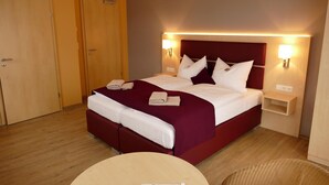 A hotel room with a large bed, two bedside tables, a round table, and a door. - Seehotel Bad Kleinen (Bad Kleinen)