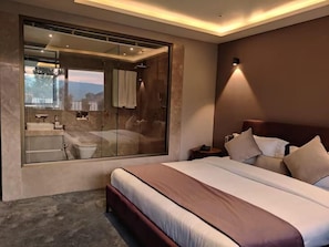 Ein modernes Schlafzimmer mit einem großen Bett, einem in Glas eingefassten Badezimmer und Blick ins Freie.