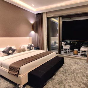 Ein Hotelzimmer mit einem großen Bett, einem Nachttisch, einer Lampe und Blick auf den Balkon.