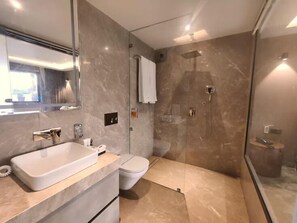 Une salle de bain moderne avec un grand miroir, un lavabo, des toilettes et une douche.