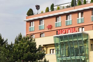 Hotel com placa vermelha, várias janelas e fachada de vidro.