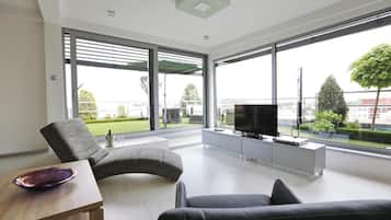 A modern living room with a sofa, a television, and a dining table with a bowl.