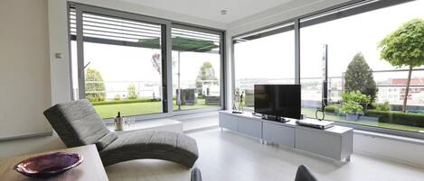 Una sala de estar moderna con un sofá, una televisión y una mesa de comedor con un tazón.