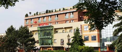 Um hotel com fachada moderna, várias janelas e um letreiro chamativo com a palavra 'HOTEL'.
