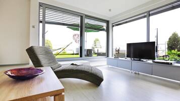 A modern living room with a sofa, a television, and a dining table.