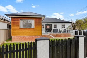 A residential property with a fenced yard, a detached garage, and a covered patio area. - The Roundabout Rest - Heart of Wagga (Wagga Wagga)