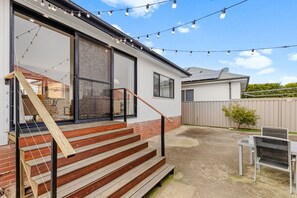 Il s’agit d’une propriété résidentielle dotée d’un escalier menant à une porte vitrée, d’une cour arrière clôturée et d’un espace salon extérieur.