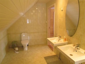 Un baño con inodoro, dos lavamanos y un espejo.