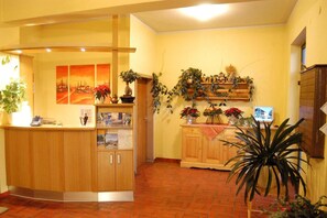 A reception area with a wooden counter, a map display, and potted plants. - Gasthof Pension Golob (Kirchbach)