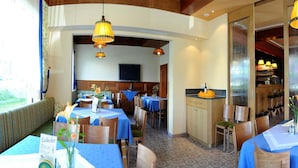 Un restaurante con varias mesas, sillas y lámparas colgantes.