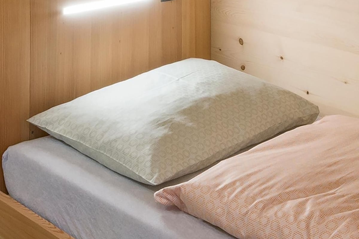 Una cama individual con un colchón y dos almohadas.