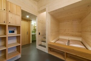 Un interior de madera con una cama, estanterías y un baño.