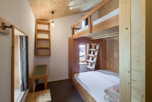 Una habitación pequeña con literas, un escritorio y una ventana.
