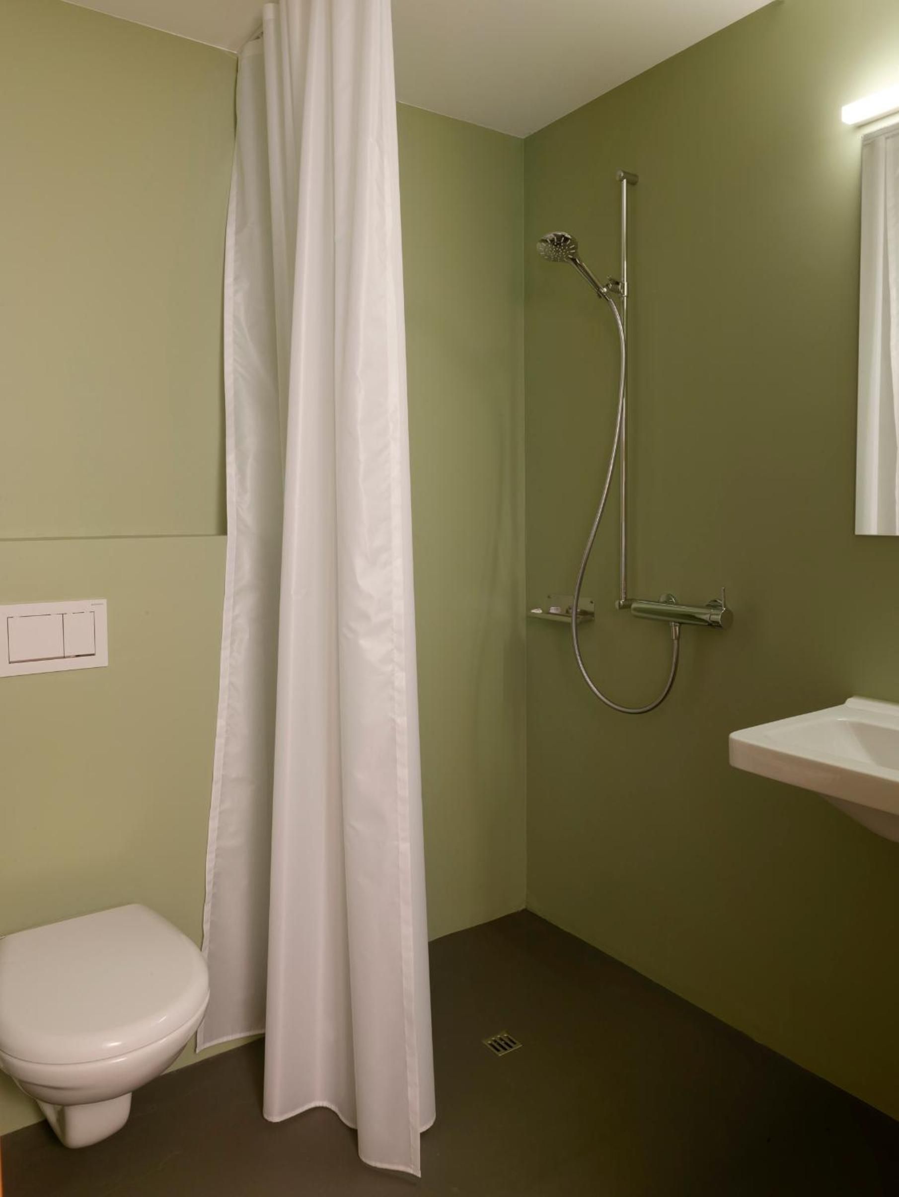 Une salle de bain avec douche, toilettes et lavabo.