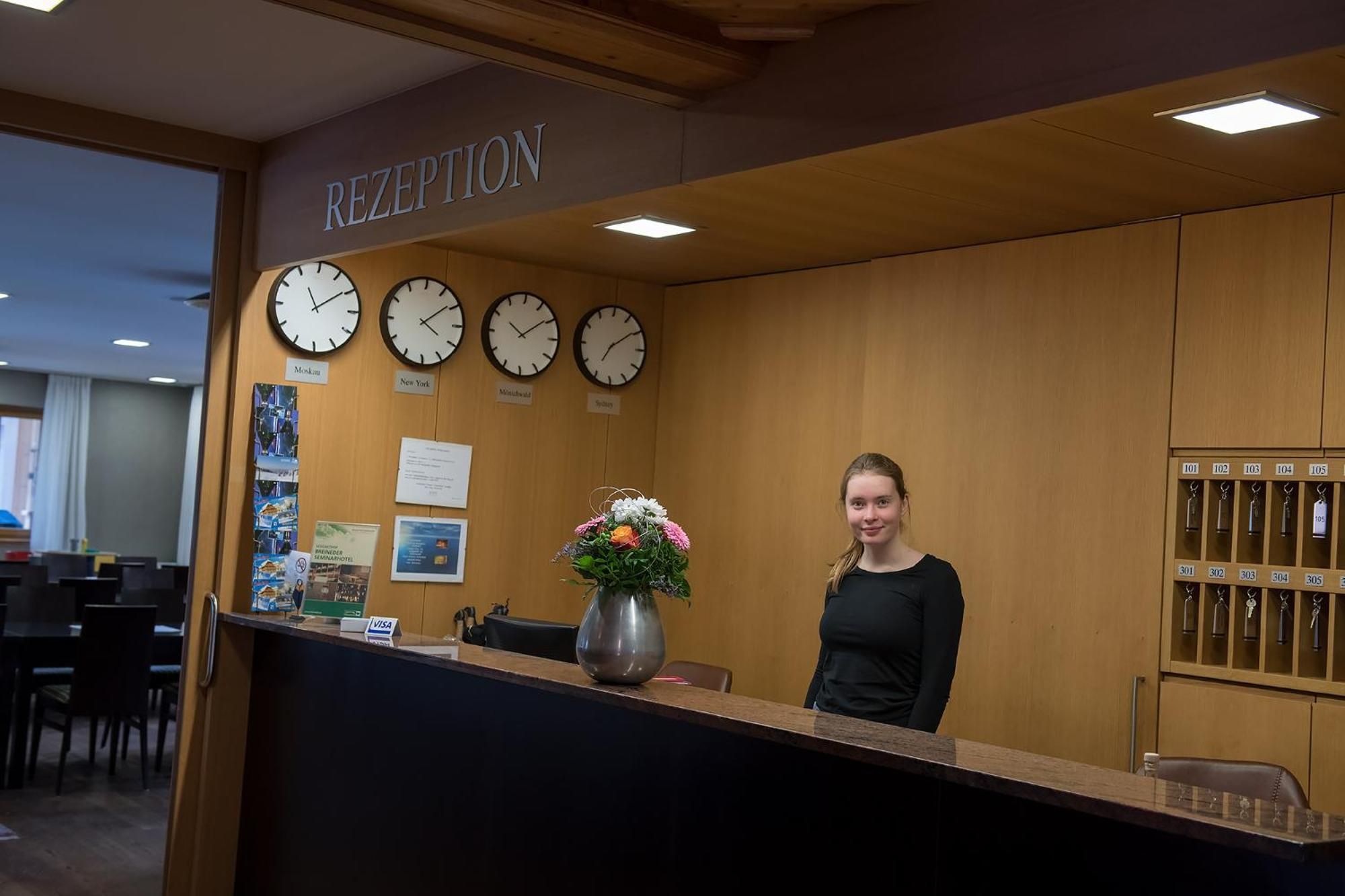 A reception desk with clocks indicating different time zones, a vase with flowers, and a sign above the desk reading 'RECEPTION'.