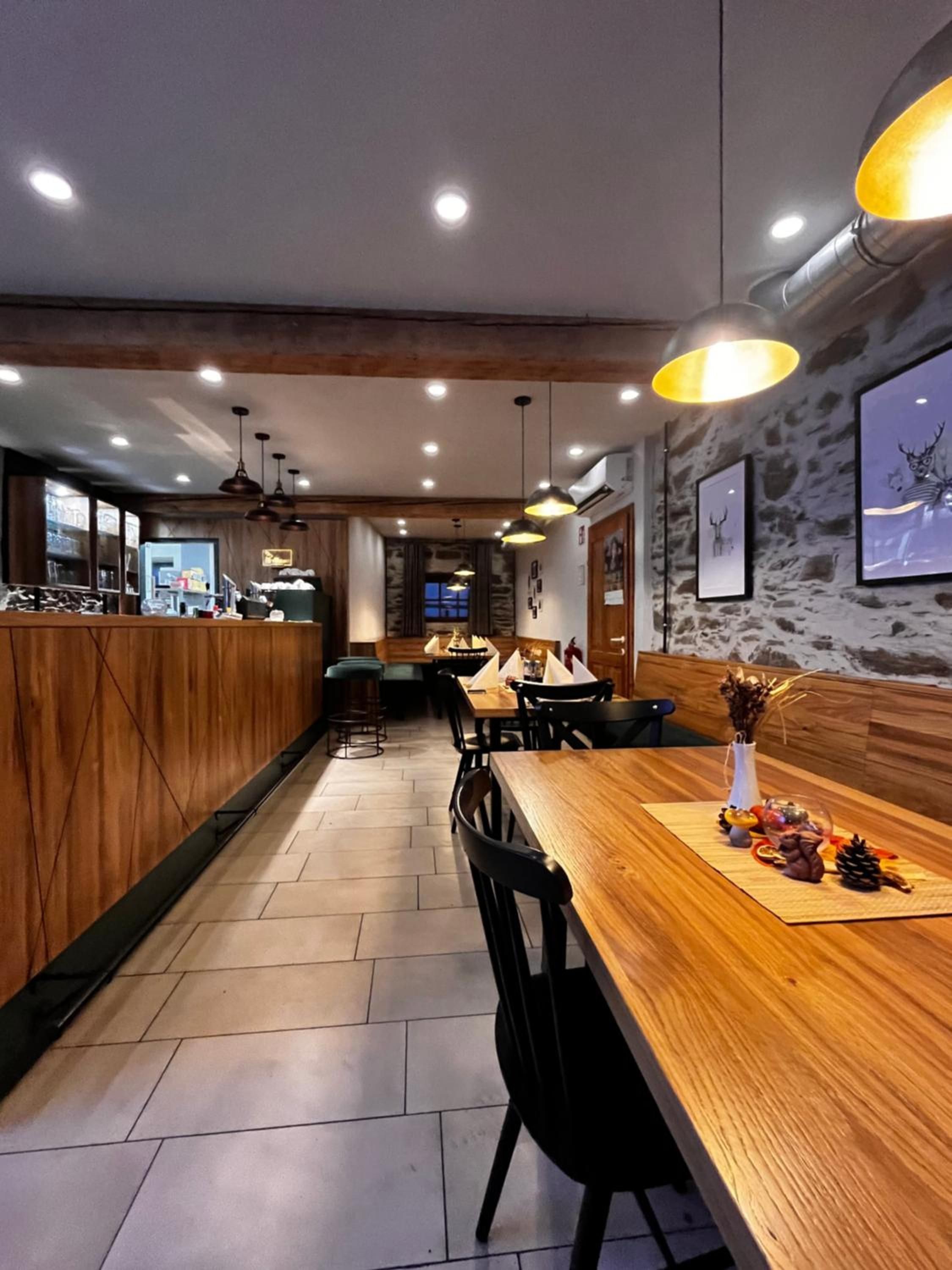 Ein Restaurantinneres mit Holzbarkeeperplatten, schwarzen Stühlen und Pendelleuchten.