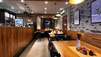 Ein Restaurantinneres mit Holzbarkeeperplatten, schwarzen Stühlen und Pendelleuchten.