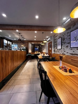 A restaurant interior with wooden bar counters, black chairs, and pendant lighting. - Seegasthof Breineder Familien Seminarhotel (Waldbach-Mönichwald)