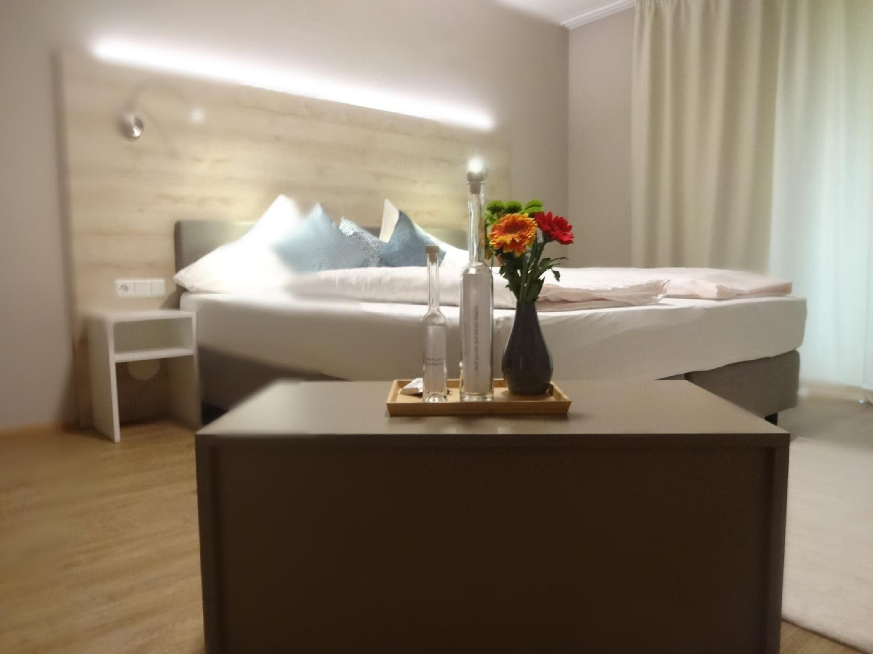 Ein Hotelzimmer mit Bett, Nachttisch und einer Blumenvase.