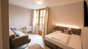 Ein Schlafzimmer mit einem Bett, einem Sessel, einer Heizung und einem fenster mit Vorhängen.