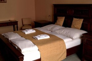 A hotel room with a large bed, a wooden headboard, and a chair. - Hotel Na Kafkovv (Ostrava)