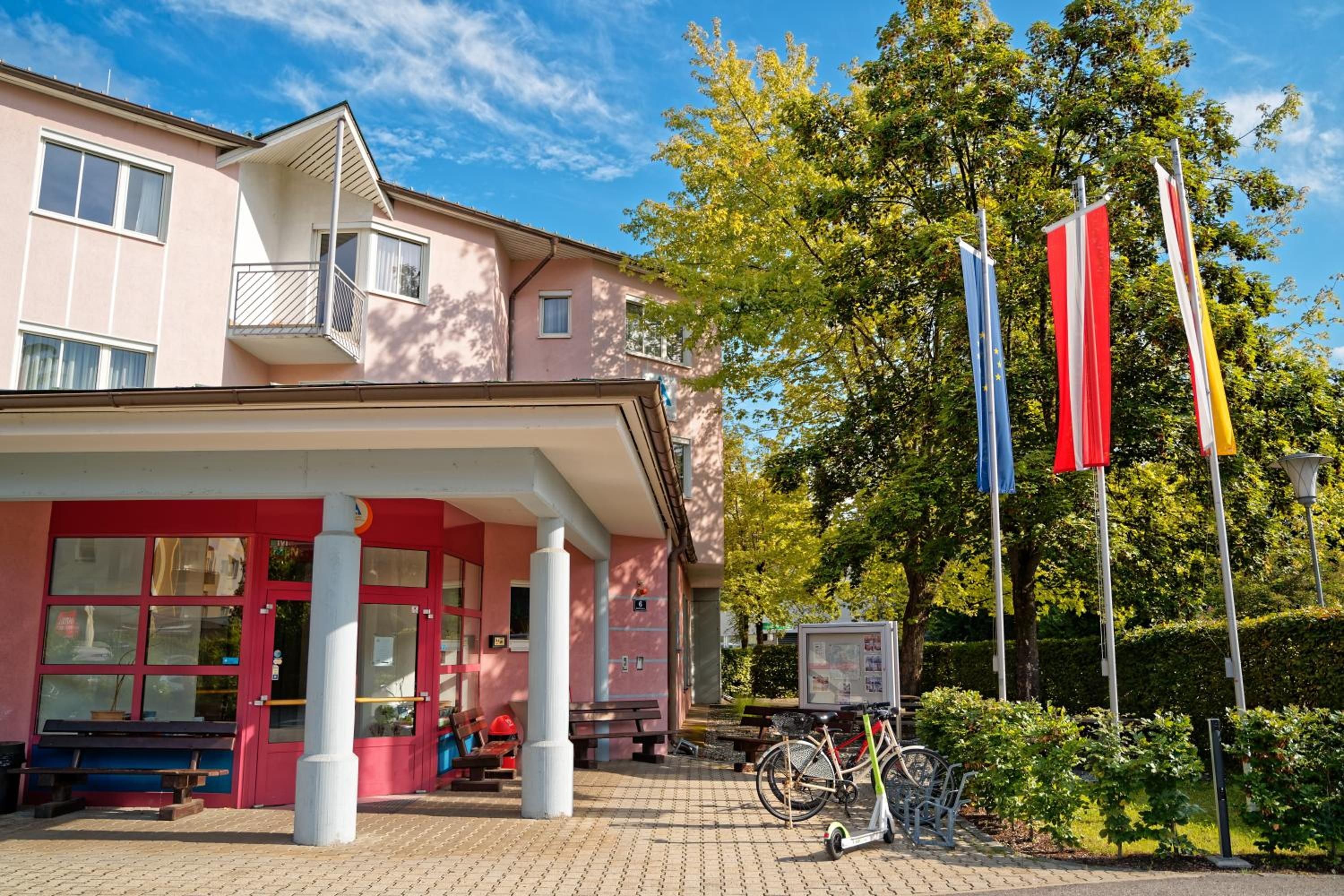 Ein Gebäude mit rosa Fassade, einem überdachten Eingang und einem Fahrrad vor der Tür.