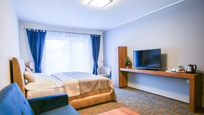 A hotel room with a bed, a TV, a sofa, and a coffee table. - Hotel Restaurant Pod Ka Tany (Krupka)