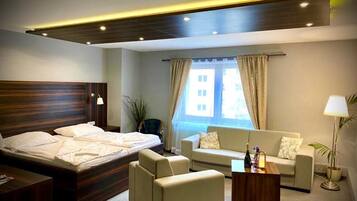 Una habitación de hotel con una cama, dos sofás, una mesita de centro y una ventana con cortinas.