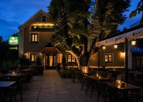 Un restaurante con mesas al aire libre, un letrero que indica que es restaurante y un árbol en el centro.