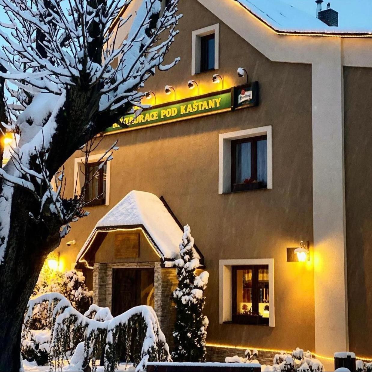 Ein Gebäude mit einem Schild, auf dem 'RESTAURACE POD KASTANY' steht, das ein Restaurant kennzeichnet.