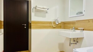 A bathroom with a dark door, a white sink, a mirror, and a towel rack. - Hotel Restaurant Pod Ka Tany (Krupka)