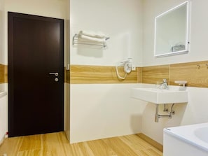 Casa de banho com porta escura, pia branca, espelho e porta-toalhas.
