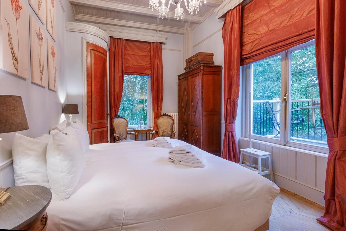 Una habitación de hotel con una cama grande, un escritorio, una silla y una ventana con cortinas.