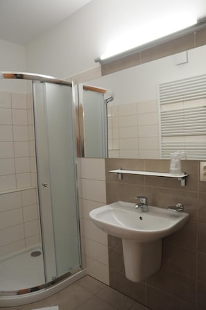 A bathroom with a glass-enclosed shower, a sink, and a mirror.