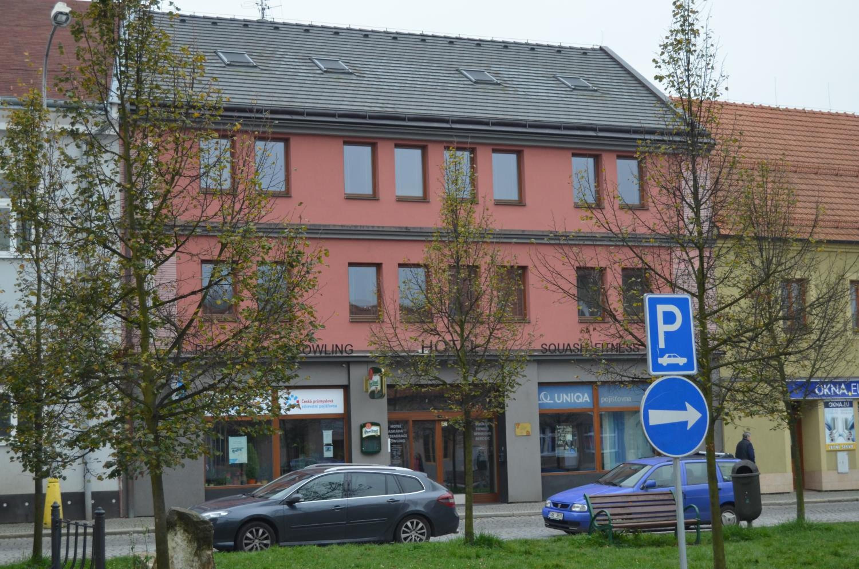 A building with a red facade, a parking sign, and a blue car parked in front.