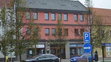 A building with a red facade, a parking sign, and a blue car parked in front.