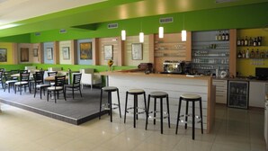 A bar area with stools, a counter, and shelves with bottles. - Hotel Kaskada (Ledeč nad Sázavou)