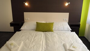 A hotel room with a large bed, two bedside tables, and two wall-mounted lights. - Hotel Kaskada (Ledeč nad Sázavou)