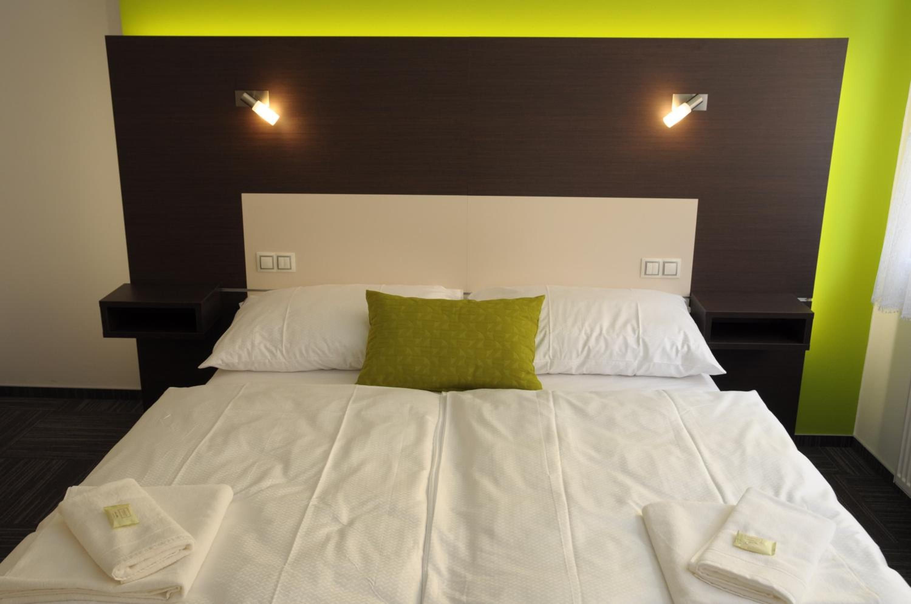 A hotel room with a large bed, two bedside tables, and two wall-mounted lights.