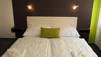 A hotel room with a large bed, two bedside tables, and two wall-mounted lights.